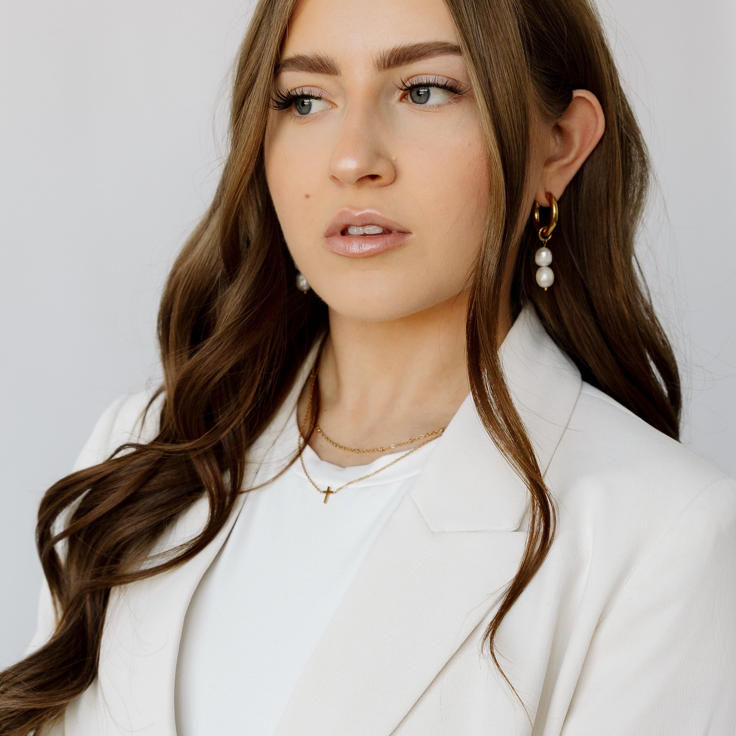 Model wearing Dainty Cross, Satellite Layering Chain, and Laura Pearl Hoops.