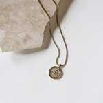 Gold necklace with a pendant on a white surface