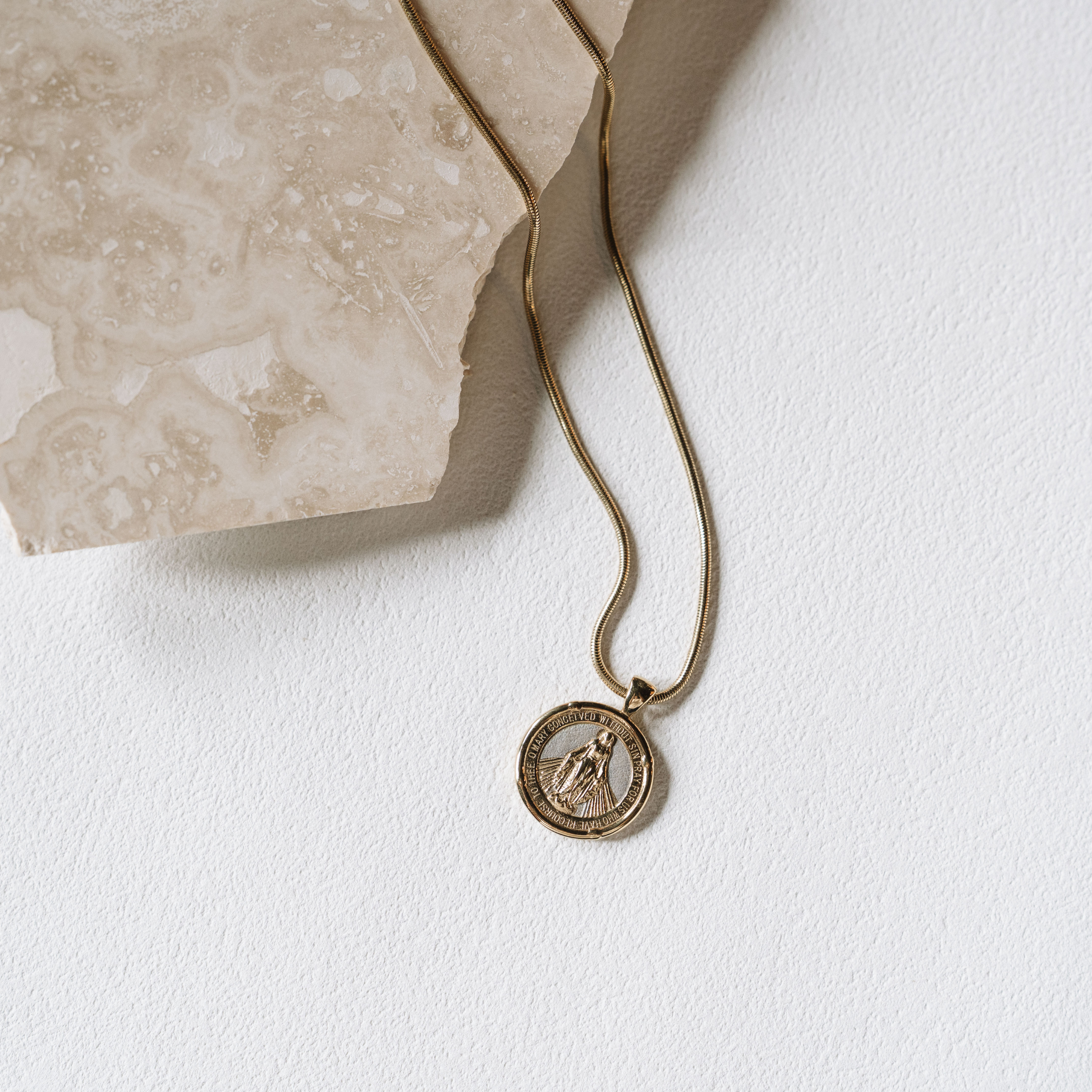 Gold necklace with a pendant on a white surface