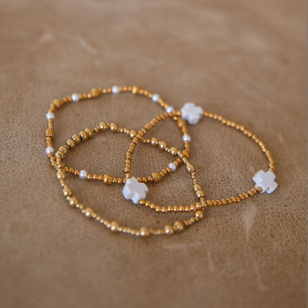 Set of 3 gold beaded bracelets with pearl and white cross bead accents.