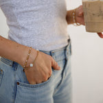 Person wearing bracelets holding a cup of coffee