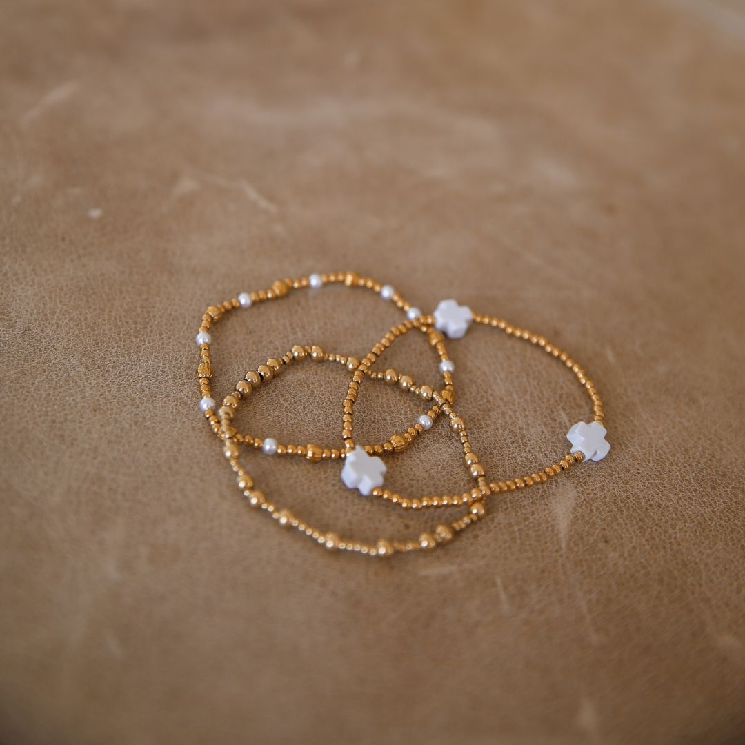 Stack of 3 bracelets gold pearls and cross