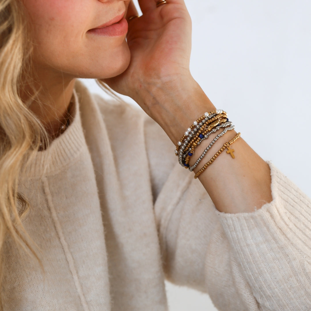 Stack of gold and silver Catholic bracelets