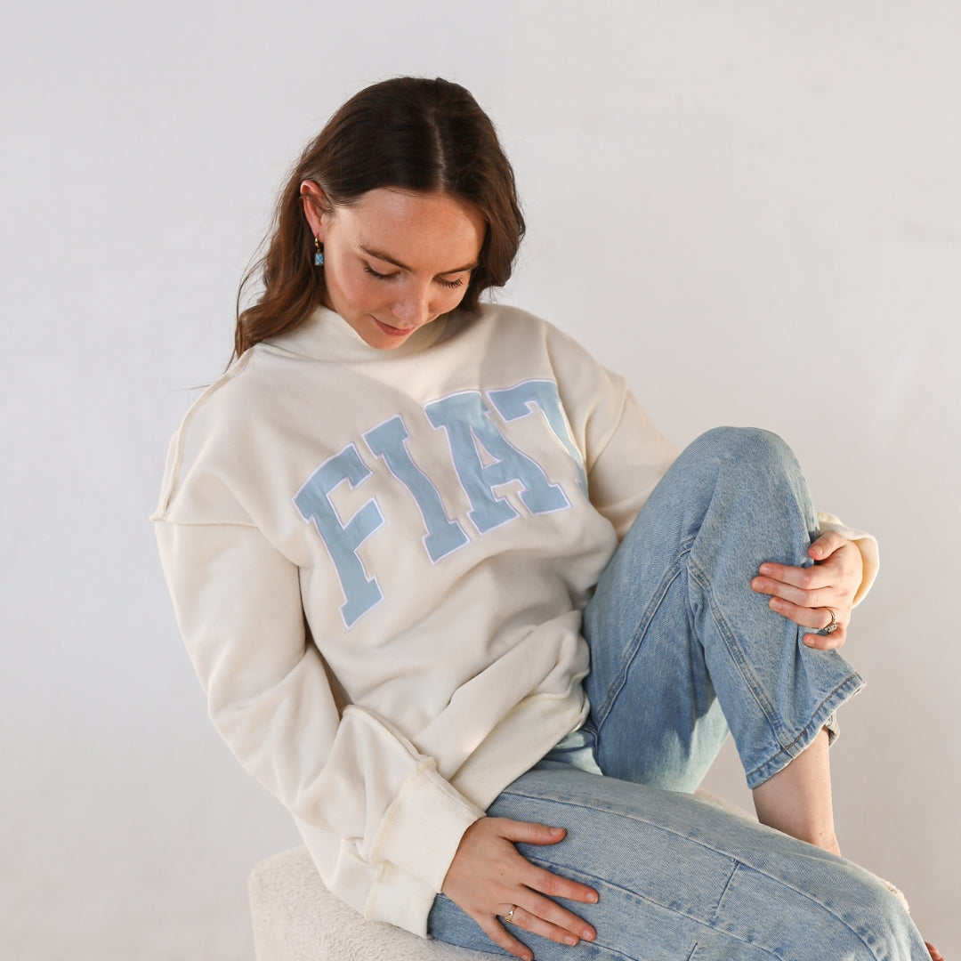 Model sitting with fiat mockneck and jeans