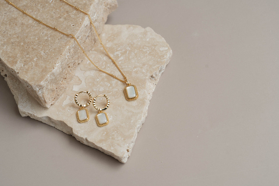 Gold earrings and necklace on rock
