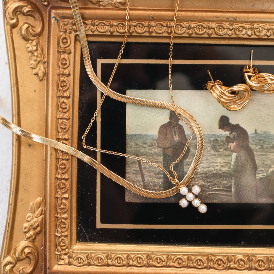 Gold slink with cross necklace on frame