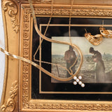 Gold slink with cross necklace on frame