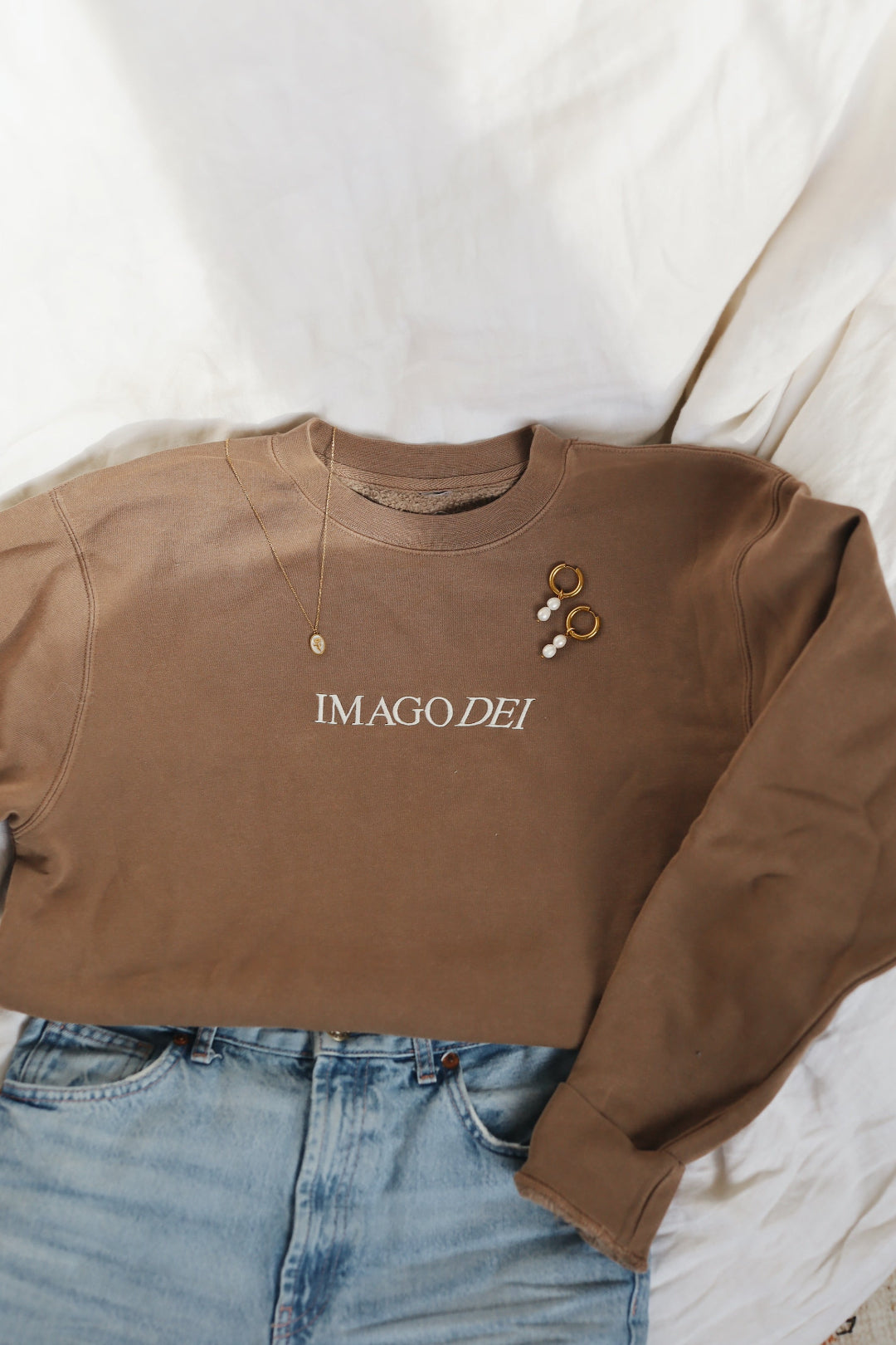 Crewneck laid with jeans, necklace and earrings