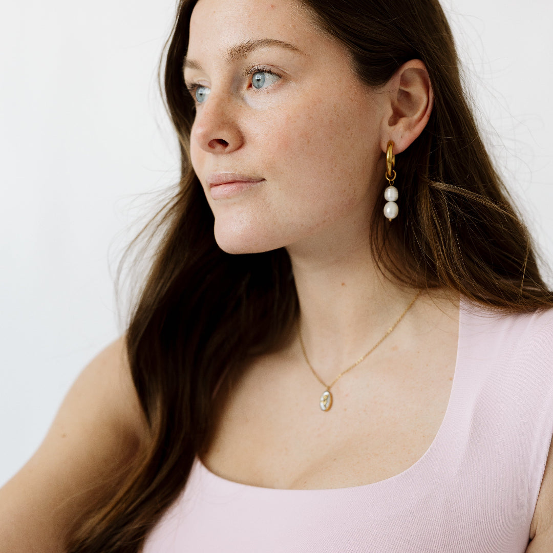 Brunette model with pearl hoops and necklace in gold