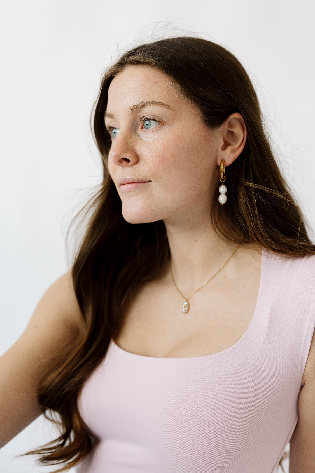 Brunette model with pearl hoops and necklace in gold