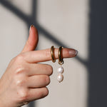 Hand showing gold pearl hoops