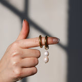 Hand showing gold pearl hoops