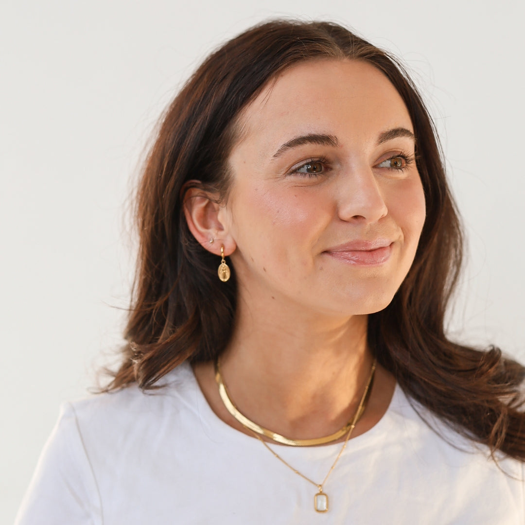 Brunette model in huggies and gold necklaces