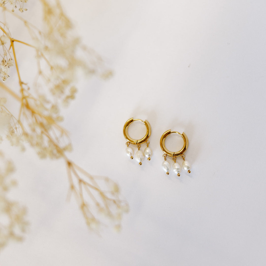 Gold and pearl earrings on white table