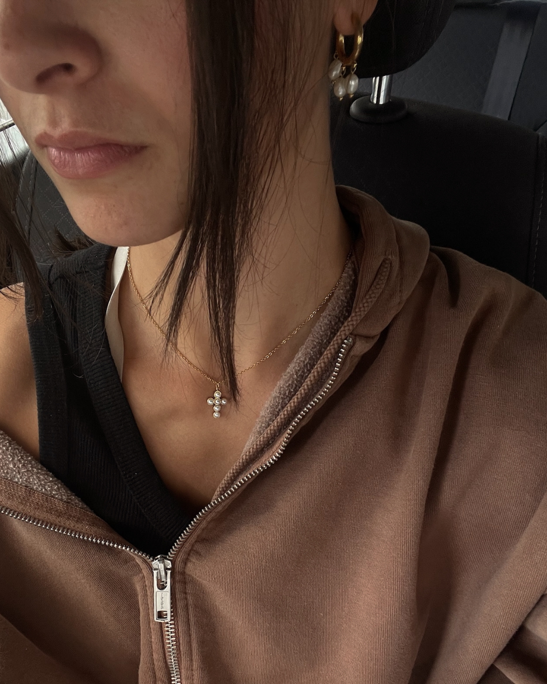 Model wearing earrings and cross necklace