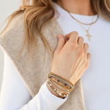 Model wearing multiple bracelet stack in both gold and silver.