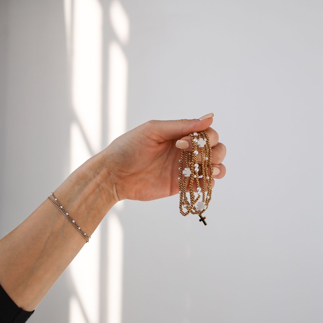 Hand holding stack of gold and pearl bracelets