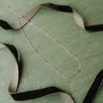 Paperclip necklace laid on green background