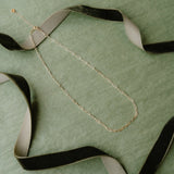 Paperclip necklace laid on green background